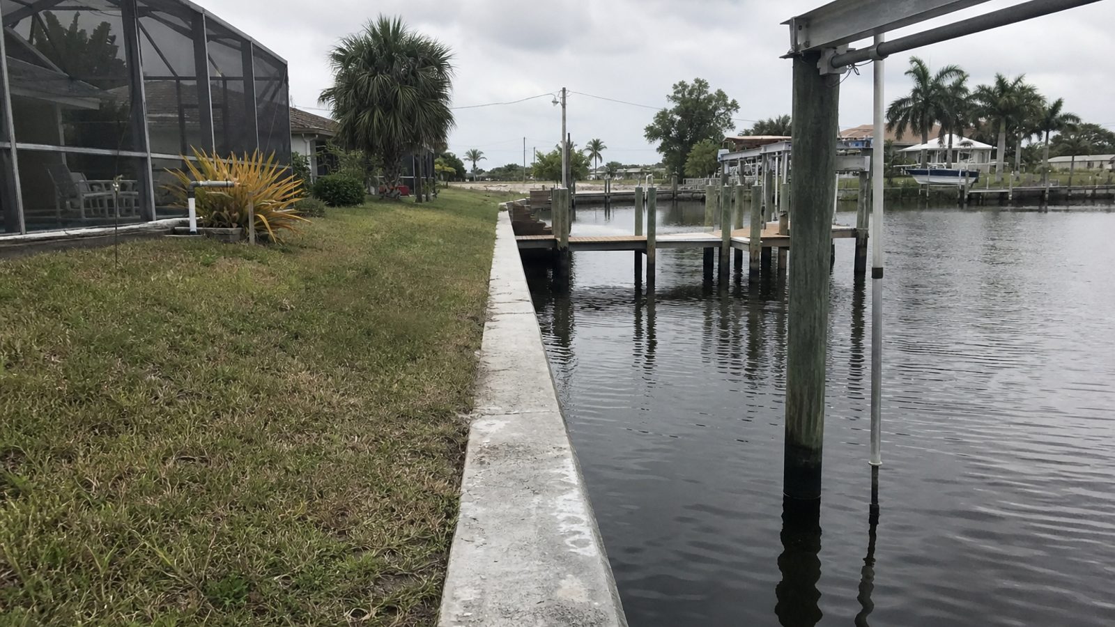 Cape Coral canal-front home with dock, boat lift, seawall, and weathered hardware