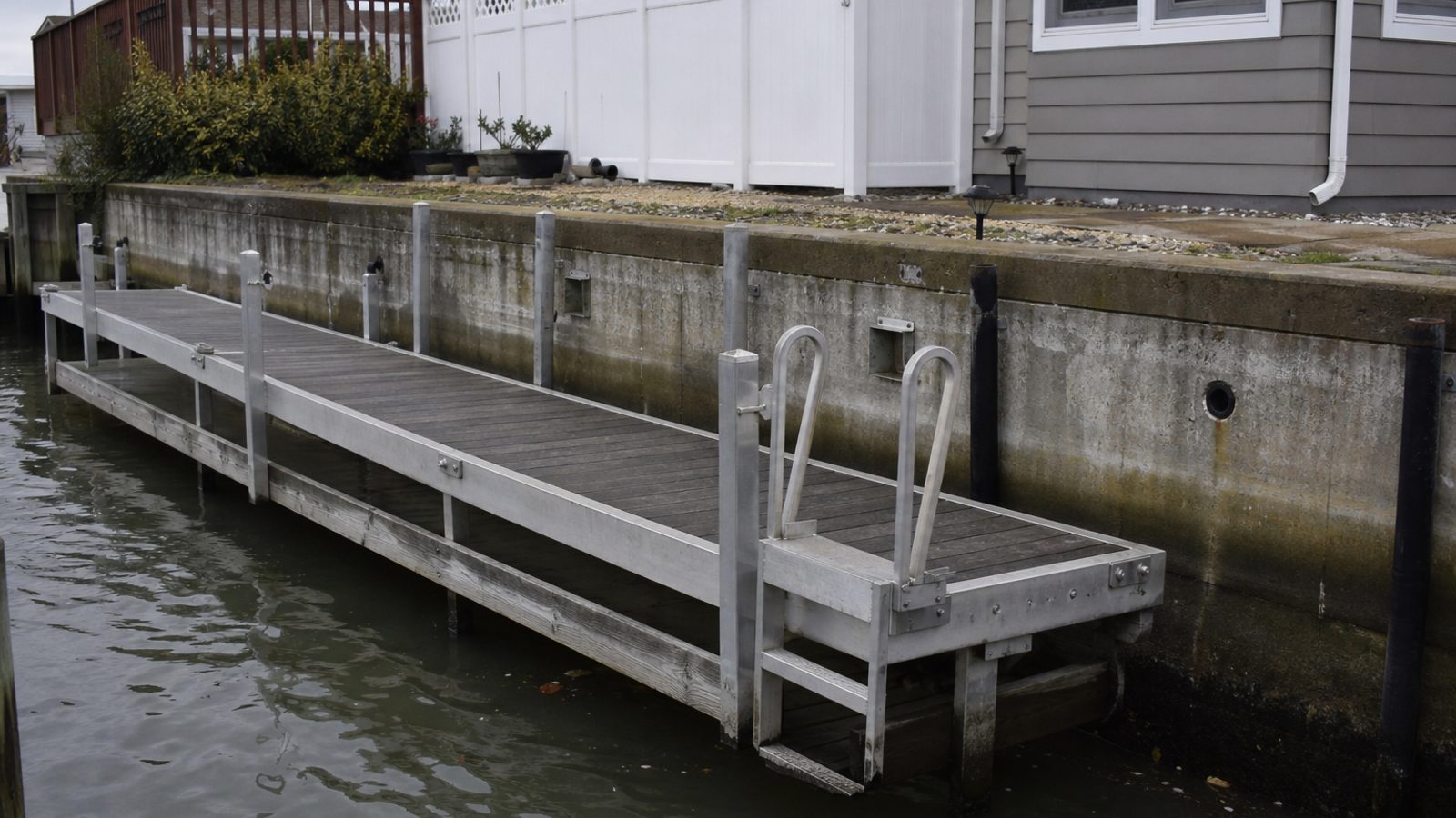 Waterfront dock hardware with salt-weathered aluminum frame, cleats, seawall staining
