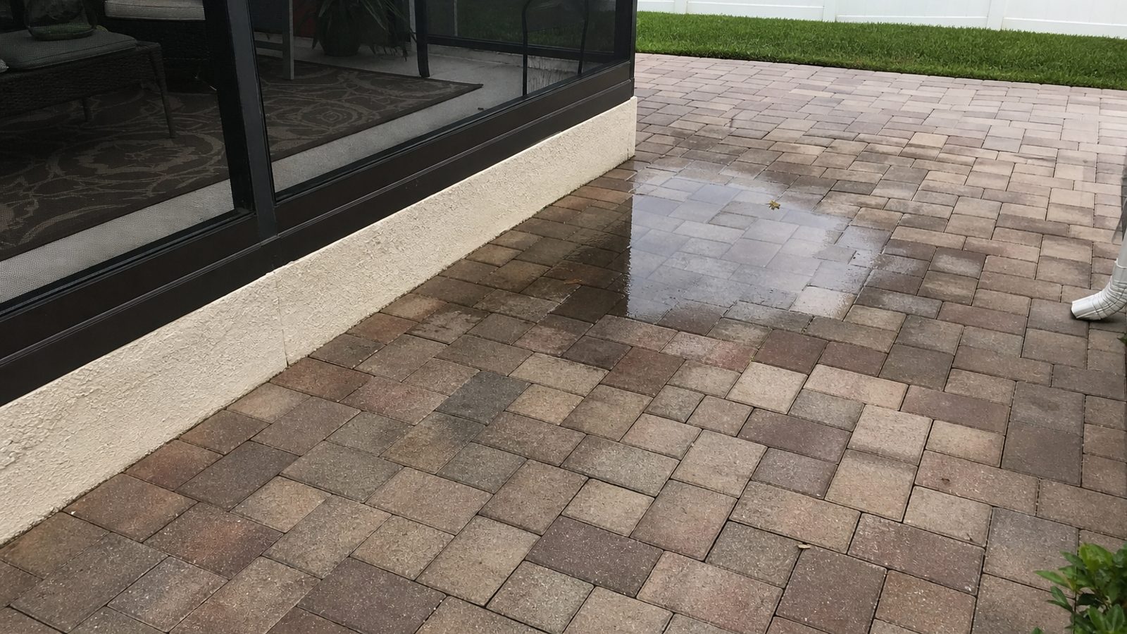 Close view of patio pavers with uneven color and water pooling mark near screened lanai
